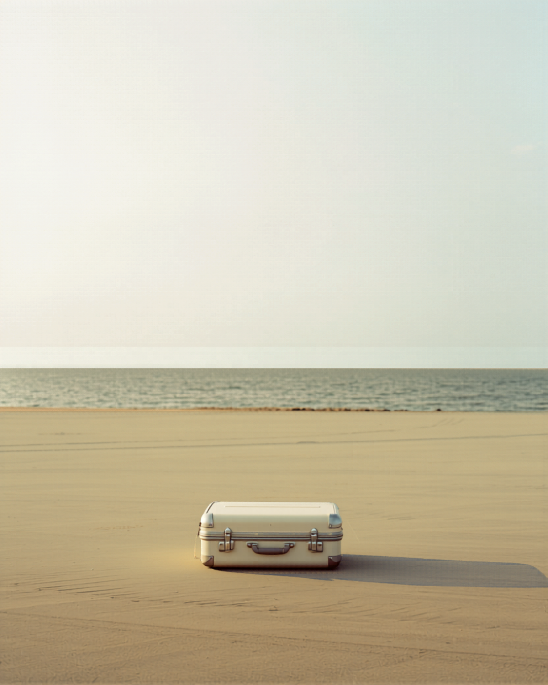 OLAS hero — bone carry-on on wet sand at coastal sunrise, mobile 4:5